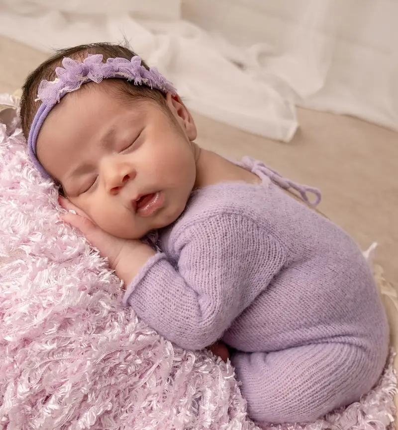 Recién nacida con enterito lila tejido, dormida