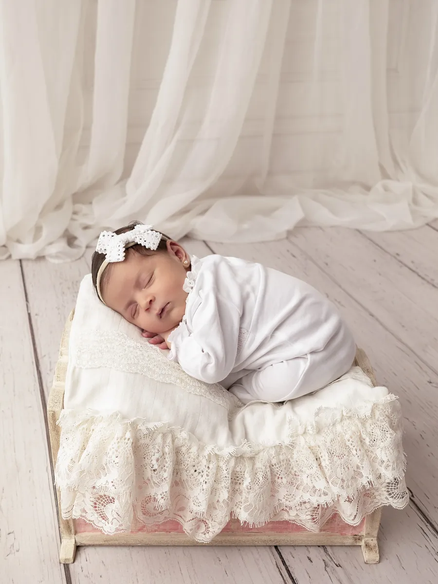 Recién nacida con moño blanco durmiendo en una canasta