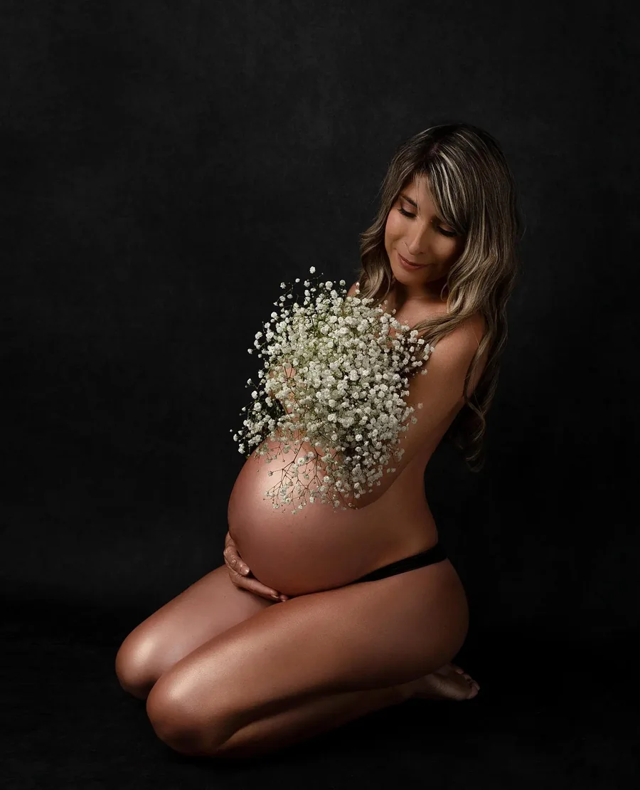 Embarazada con flores sobre la panza, con fondo oscuro