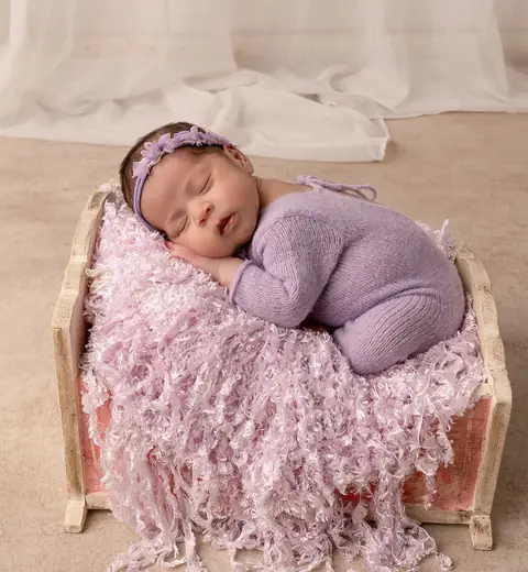 Recién nacida con enterito lila en una cajita de madera